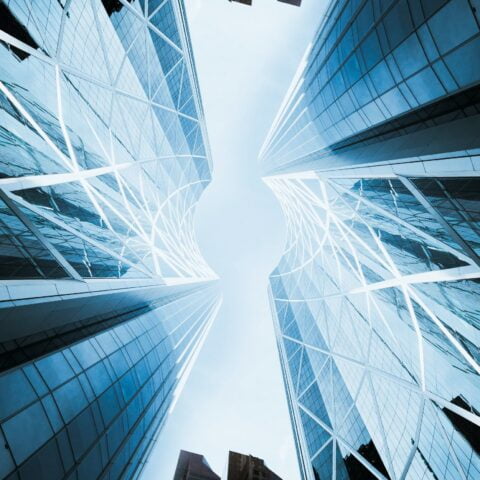 Ground view looking towards the sky of 4 glass skyscrapers that are forming a circle in the centre